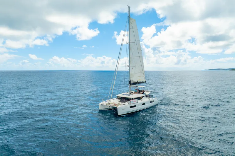 Slide: The Image of 2023 Lagoon 46 catamaran sailing on open ocean under a partly cloudy sky. - 132