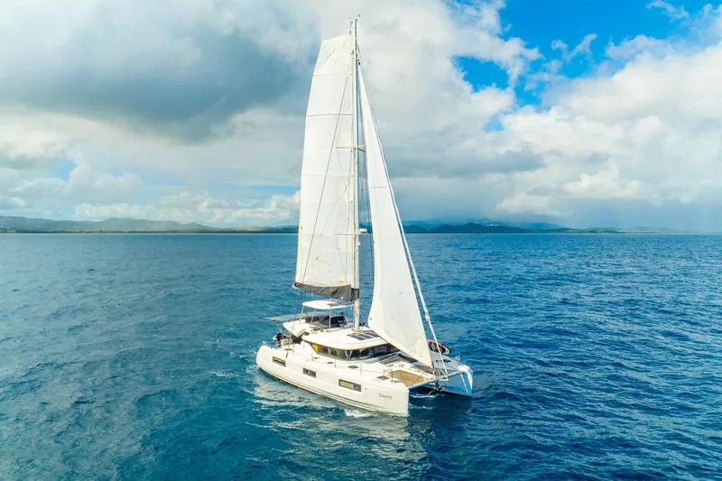 Slide: The Image of 2023 Lagoon 46 catamaran sailing on open ocean under a partly cloudy sky. - 133