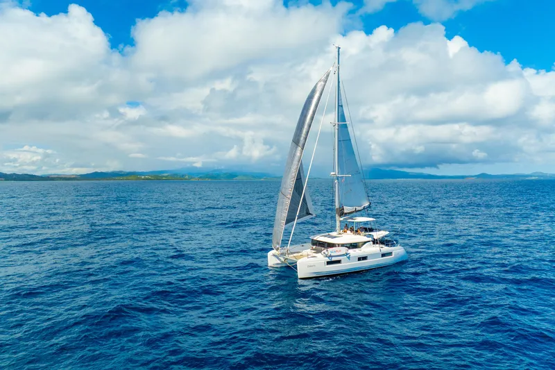 Slide: The Image of 2023 Lagoon 46 catamaran sailing on open ocean under clear blue sky. - 135