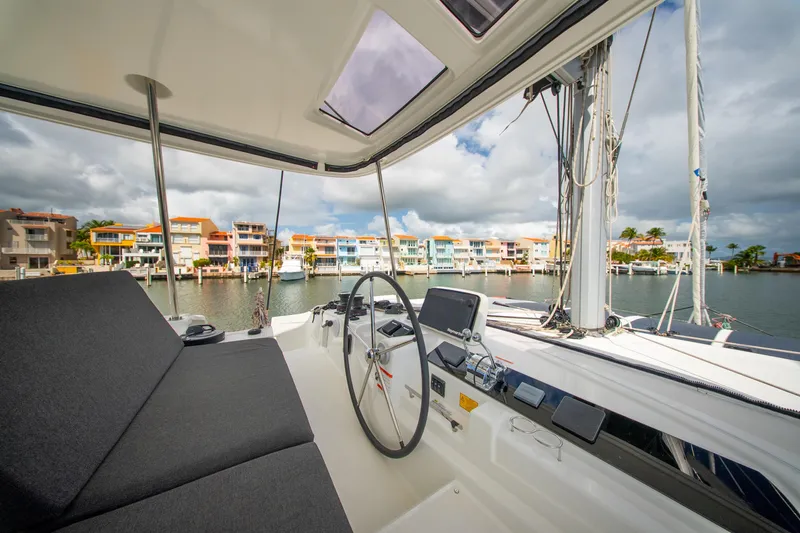 Slide: The Image of 2023 Lagoon 46 catamaran helm with waterfront view and colorful buildings. - 14