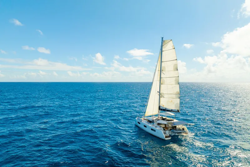 Slide: The Image of 2023 Lagoon 46 catamaran sailing on open ocean under clear blue sky. - 2