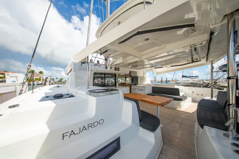 Slide: The Image of 2023 Lagoon 46 catamaran with spacious deck and seating area, docked at marina. - 29