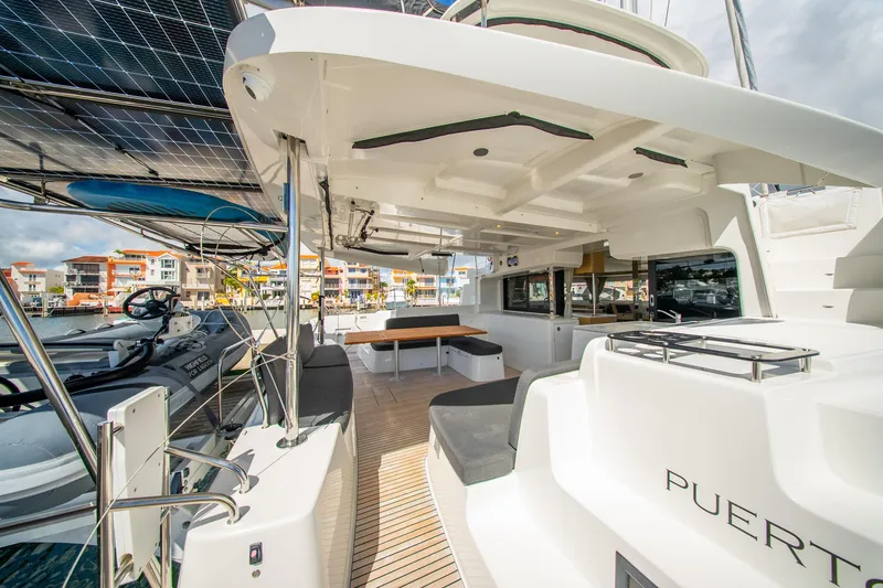 Slide: The Image of 2023 Lagoon 46 catamaran with spacious deck, solar panels, and modern seating in a marina setting. - 30