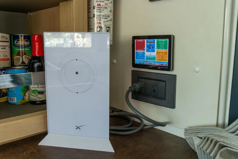 Slide: The Image of Control panel and Starlink router inside 2023 Lagoon 46 yacht kitchen cabinet. - 49