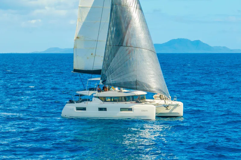 Slide: The Image of 2023 Lagoon 46 catamaran sailing on open blue sea with distant islands. - 5