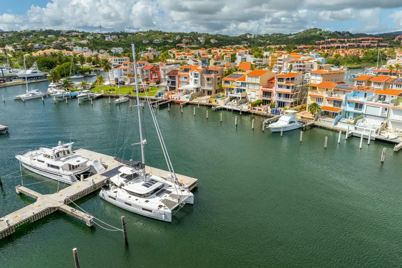 Slide: The Image of Aerial view of 2023 Lagoon 46 catamaran docked in vibrant marina with colorful waterfront homes. - 7