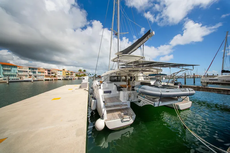 Slide: The Image of 2023 Lagoon 46 catamaran docked at a marina under a partly cloudy sky. - 8