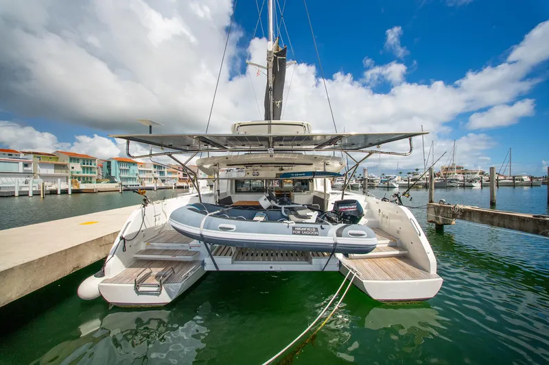 Slide: The Image of 2023 Lagoon 46 catamaran docked at marina, featuring inflatable boat and clear blue sky. - 9