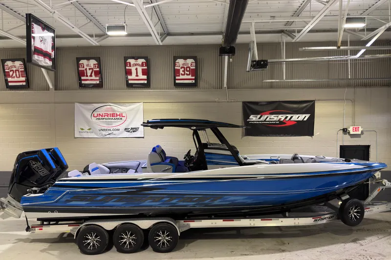Slide: The Image of 2025 Sunsation 32 CCX boat in showroom, blue exterior, on trailer, with sports memorabilia. - 3