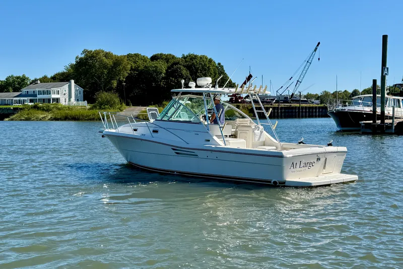 Slide: The Image of 2000 Pursuit 3000 Express boat on calm water near a dock, under clear blue sky. - 1