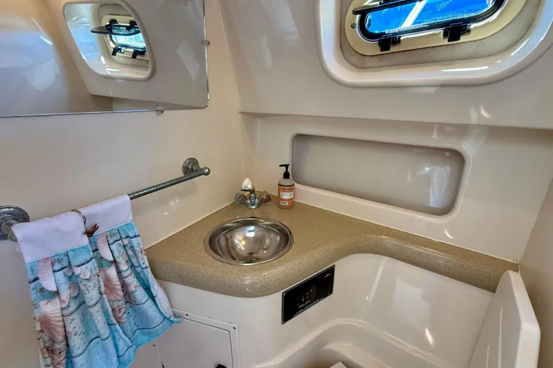Slide: The Image of 2000 Pursuit 3000 Express boat bathroom with sink, mirror, and porthole window. - 12