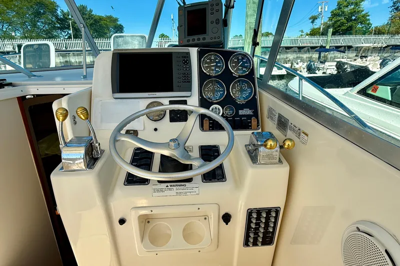 Slide: The Image of Control panel of a 2000 Pursuit 3000 Express boat with steering wheel and gauges. - 3
