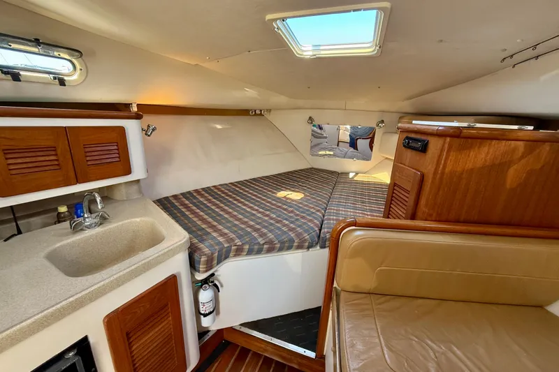 Slide: The Image of 2000 Pursuit 3000 Express cabin interior with bed, sink, and seating area. - 5