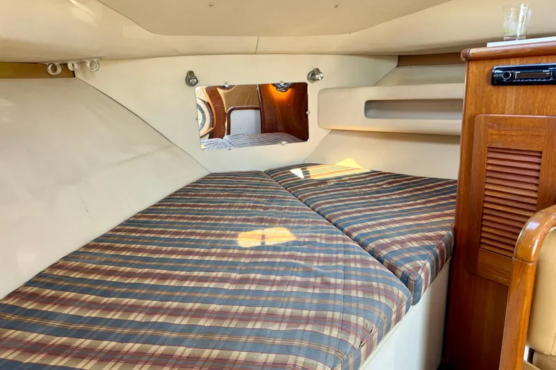 Slide: The Image of 2000 Pursuit 3000 Express cabin interior with striped bedding and wooden cabinetry. - 6