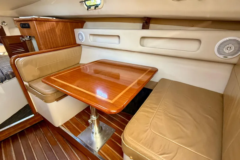 Slide: The Image of 2000 Pursuit 3000 Express cabin with wooden table and beige seating. - 7