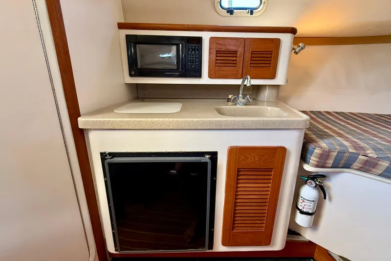 Slide: The Image of Compact kitchen area in a 2000 Pursuit 3000 Express boat with sink, microwave, and storage. - 8