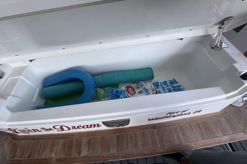 Slide: The Image of Open storage compartment on Cobalt R35 boat with pool noodles and ice packs. - 12