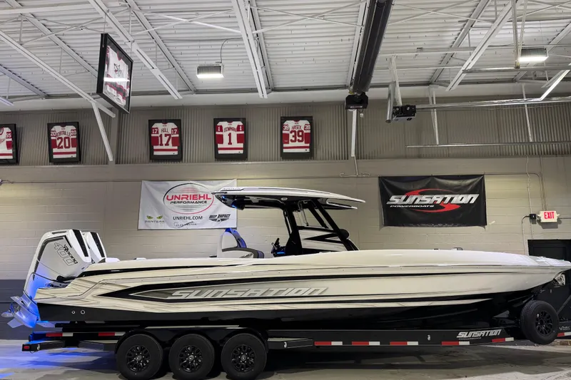 Slide: The Image of 2026 Sunsation 32 CCX boat in showroom, sleek design, on trailer, sports memorabilia background. - 4