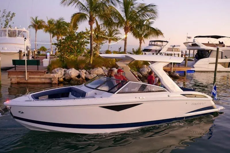 The Image of 2026 Cobalt A29 boat cruising near a marina with palm trees at sunset. - 1