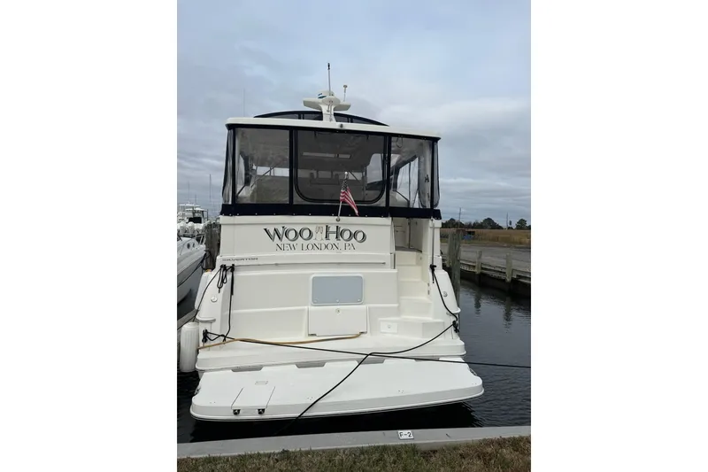 Slide: The Image of 2000 Silverton 392 Motor Yacht docked, rear view with "Woo Hoo" name and American flag. - 2