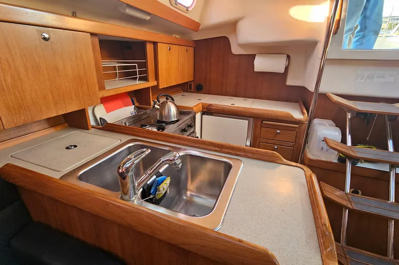 Slide: The Image of Interior of a 2005 Catalina 350 sailboat kitchen with wooden cabinetry and stainless steel sink. - 30