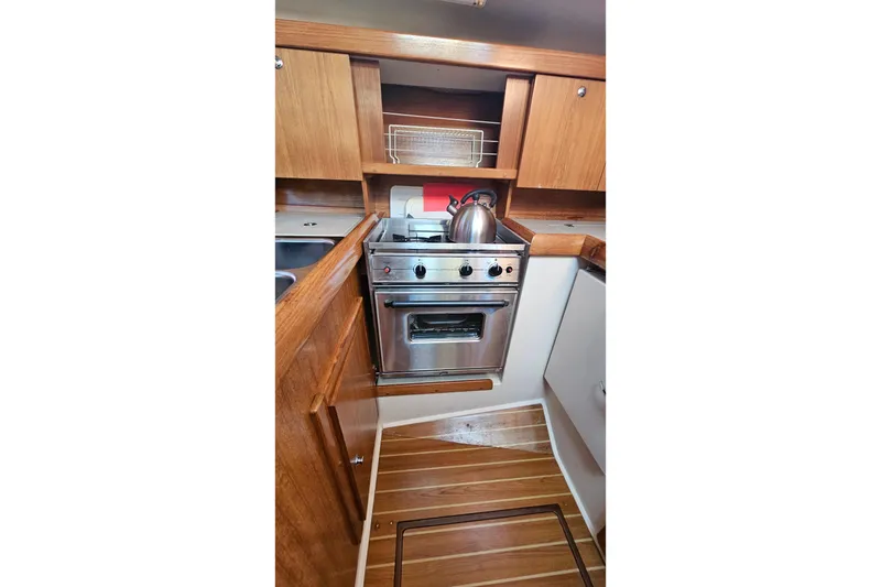 Slide: The Image of Compact kitchen in a 2005 Catalina 350 sailboat with stove and wooden cabinetry. - 32