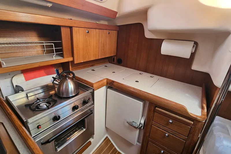Slide: The Image of Compact kitchen in a 2005 Catalina 350 sailboat with stove, kettle, and wooden cabinetry. - 33