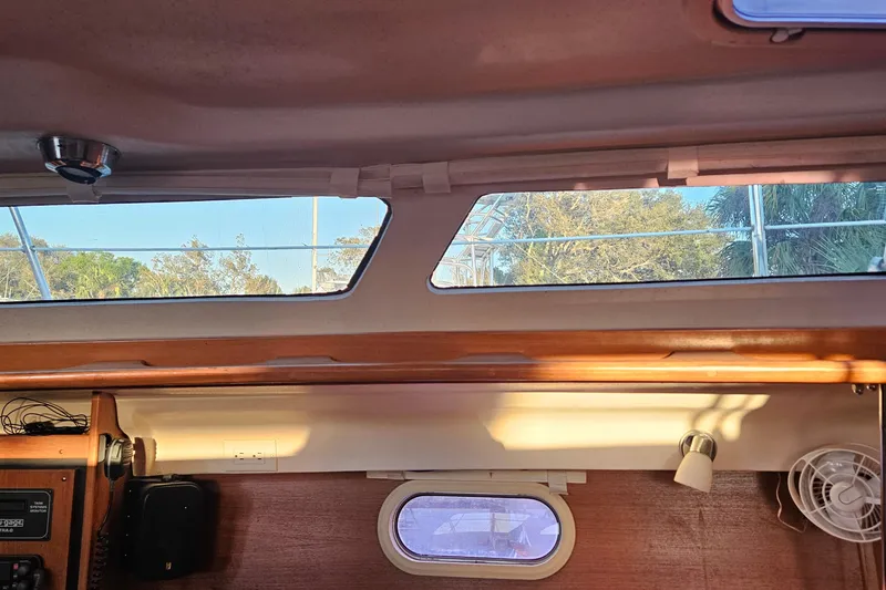 Slide: The Image of Interior view of a 2005 Catalina 350 sailboat cabin with windows and wooden accents. - 54