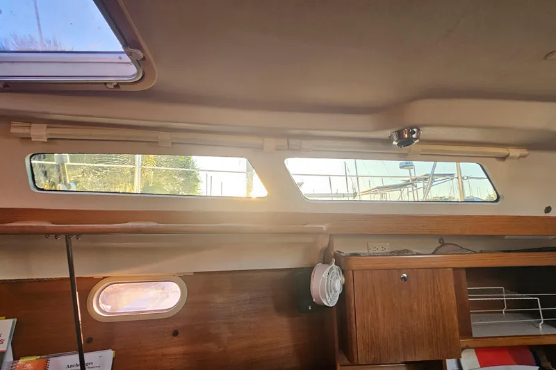 Slide: The Image of Interior view of a 2005 Catalina 350 sailboat, featuring windows and wooden cabinetry. - 55