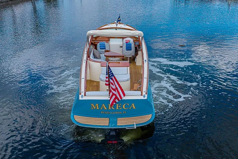 Slide: The Image of 2004 Hinckley Talaria 29 R boat cruising on a sunny waterfront with palm trees. - 2
