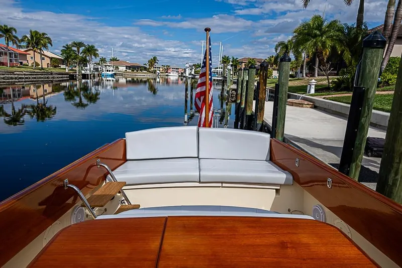 Slide: The Image of 2004 Hinckley Talaria 29 R boat docked, featuring elegant seating and wooden accents under a clear sky. - 11