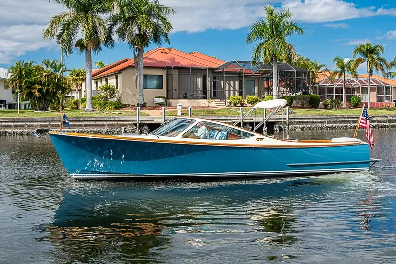 Slide: The Image of 2004 Hinckley Talaria 29 R boat cruising on a sunny waterfront with palm trees. - 16