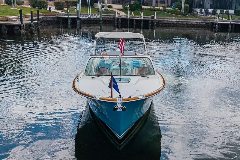 Slide: The Image of 2004 Hinckley Talaria 29 R boat on calm water, front view with flags. - 17