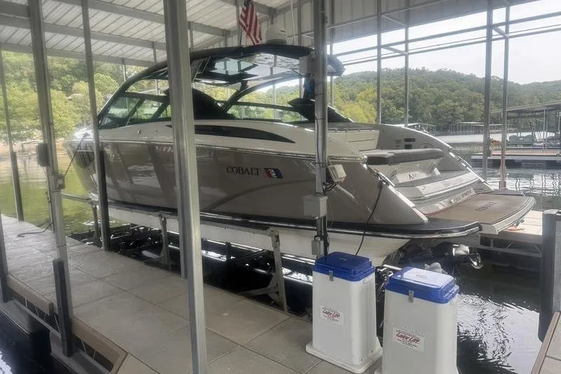 The Image of 2022 Cobalt A36BR boat docked in a covered marina with scenic background. - 0