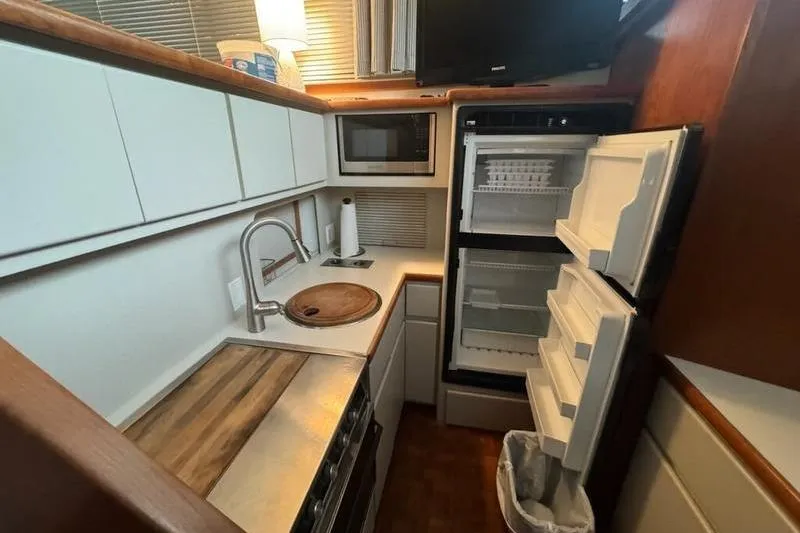 Slide: The Image of 1992 Carver 38 Aft Cabin Motor Yacht kitchen with open fridge, microwave, and sink. - 4