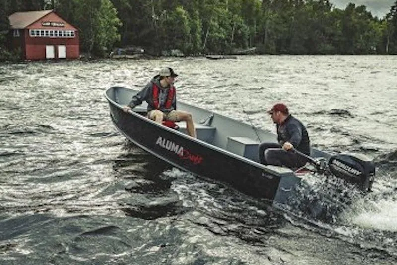 Slide: The Image of 2026 Alumacraft V16 boat on a lake with two people, near a red boathouse. - 3