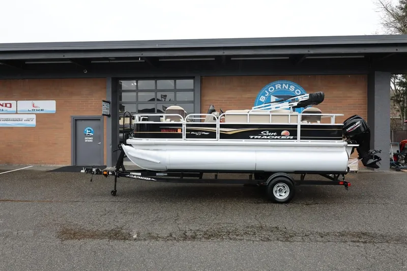 The Image of 2022 Sun Tracker Bass Buggy 18 DLX pontoon boat on trailer outside dealership. - 1