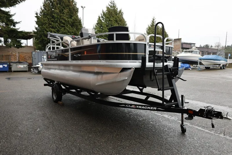 Slide: The Image of 2022 Sun Tracker Bass Buggy 18 DLX pontoon boat on trailer in parking lot. - 4