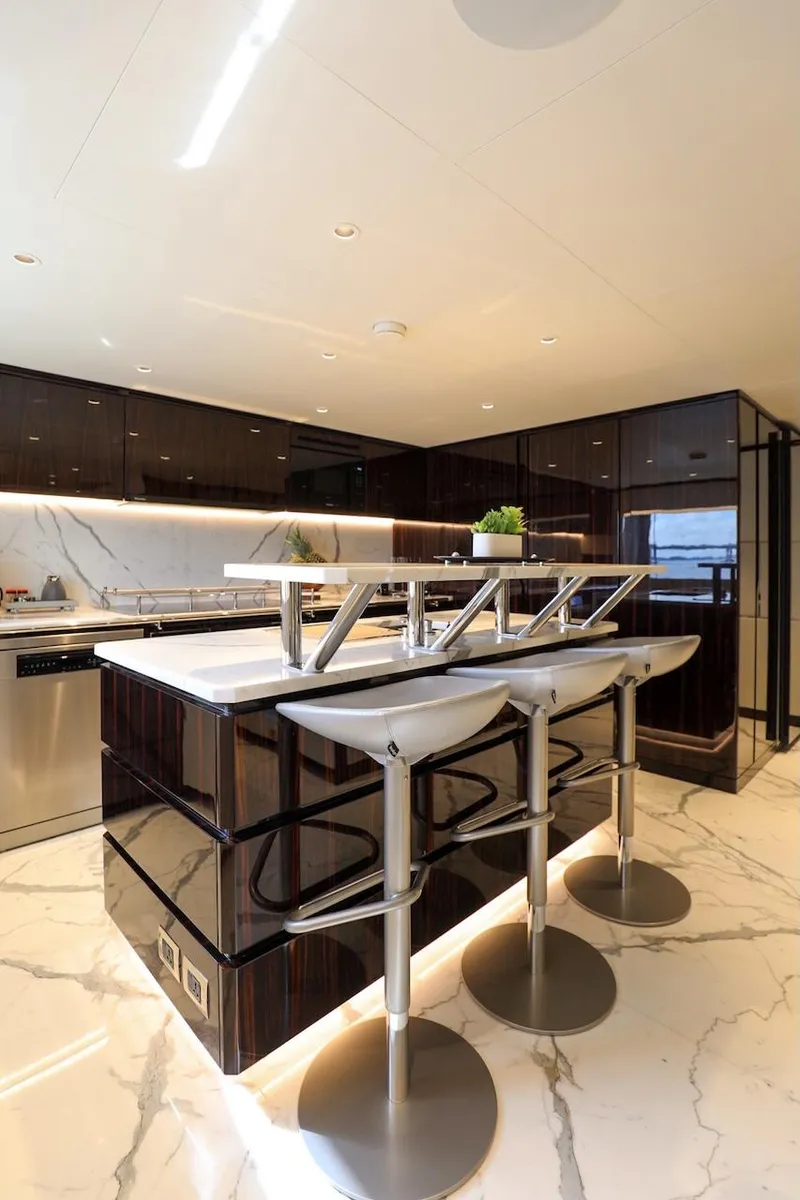 Slide: The Image of Luxurious 2025 Majesty 120 yacht kitchen with modern bar stools and sleek marble flooring. - 31