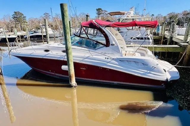 The Image of 2006 Sea Ray 340 Sundancer boat docked with red canopy in a marina. - 1
