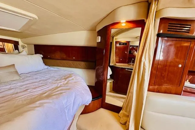 Slide: The Image of 2006 Sea Ray 340 Sundancer cabin interior with bed, wood paneling, and cozy lighting. - 26