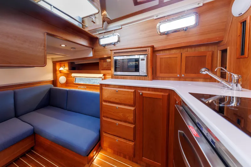 Slide: The Image of 2022 Sabre 38 SE yacht interior with wooden cabinetry, blue seating, and modern kitchen amenities. - 17