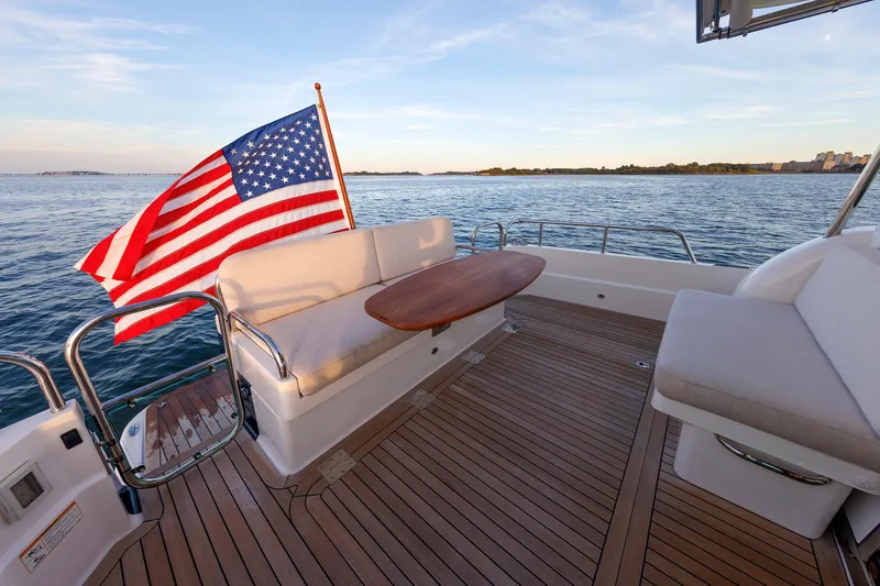 Slide: The Image of 2022 Sabre 38 SE yacht deck with American flag, wooden table, and ocean view. - 8