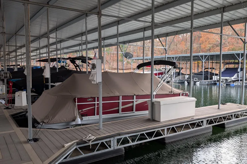 Slide: The Image of Covered Crest CHILLER CP2 boat docked in a marina, surrounded by calm water and autumn trees. - 16