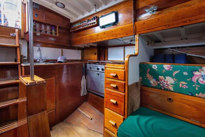 Slide: The Image of Interior of 1957 Sparkman & Stephens K/CB Yawl, featuring wooden cabinetry and floral upholstery. - 12