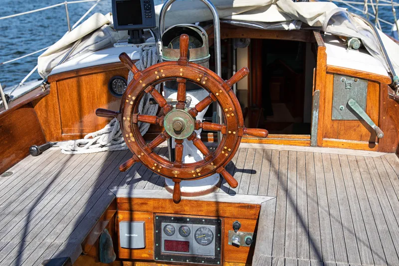 Slide: The Image of 1957 Sparkman & Stephens K/CB Yawl wooden helm on deck, showcasing classic nautical design. - 22