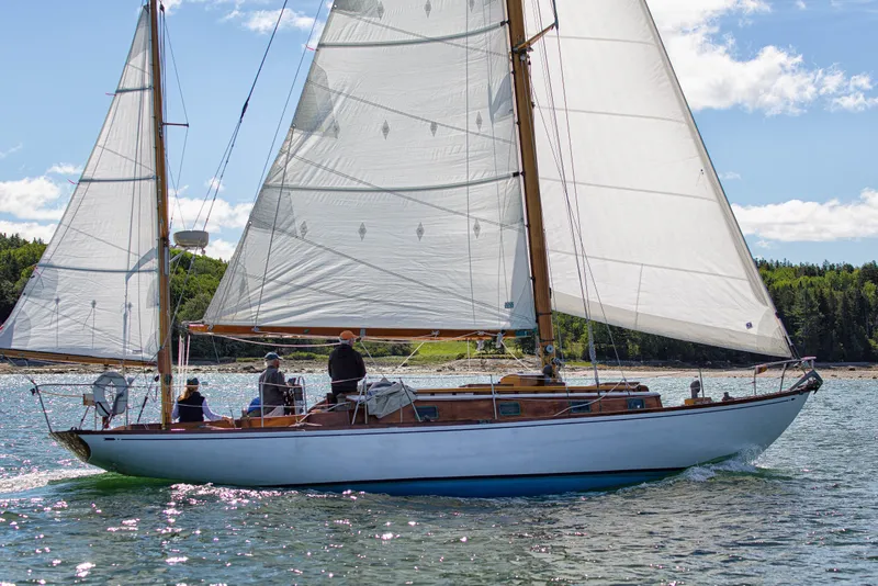 Slide: The Image of 1957 Sparkman & Stephens K/CB Yawl sailing on a sunny day with lush green shoreline. - 29