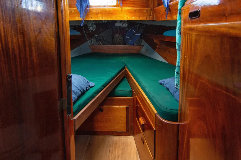 Slide: The Image of 1957 Sparkman & Stephens K/CB Yawl cabin with green cushions and wooden interior. - 6