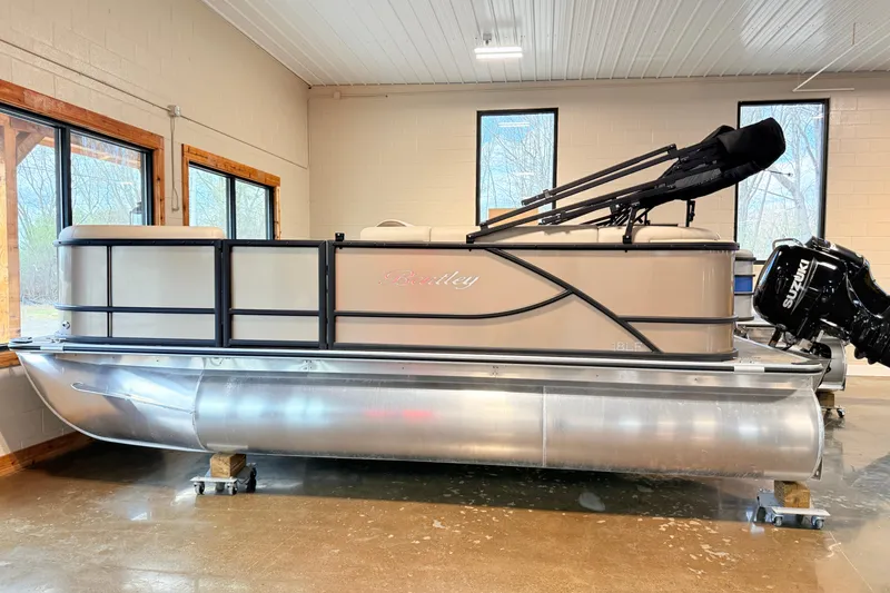 The Image of 2026 Bentley Pontoons LE 180CR in showroom, side view with Suzuki outboard motor. - 2