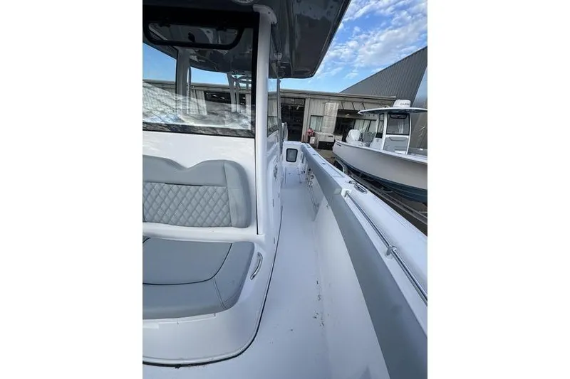 Slide: The Image of 2026 Sportsman Open 282 Center Console boat, sleek design, docked near a warehouse. - 17